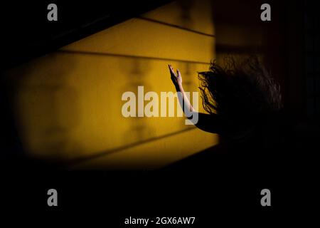 Silhouette einer Frau, verzweifelt, mit einem Arm in der Luft und fliegenden Haaren. Mystery Night Scene. Stockfoto
