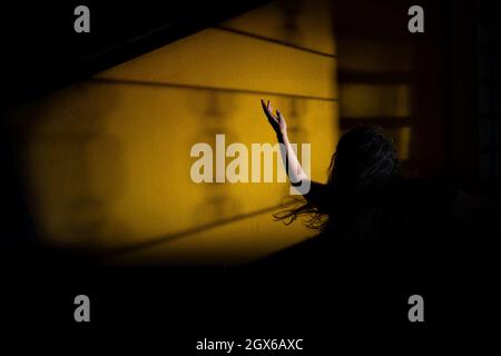 Silhouette einer Frau, verzweifelt, mit einem Arm in der Luft und fliegenden Haaren. Mystery Night Scene. Stockfoto