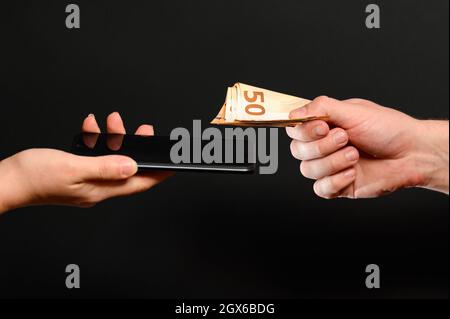 Ein Beispiel für den Einzelhandel mit Smartphones, die Zahlung von Waren in bar, das Empfangen von Geld für verkaufte Waren. Neu Stockfoto