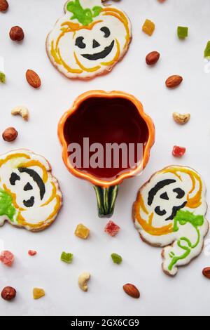 Halloween Kreativkonzept: Kürbisbecher und hausgemachte Kekse in Form von niedlichen Kürbissen und GeisterNahaufnahme. Ästhetische Herbststimmung oder Trick or Treat Konz Stockfoto