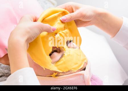 Der Prozess der Entfernung der kosmetischen goldenen Masse, kosmetische Verfahren im Salon. Neu Stockfoto