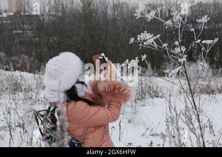 Mädchen auf einem Spaziergang im Winter Park. Fotografien Pflanzen bedeckt mit Frost und Schnee. Stockfoto
