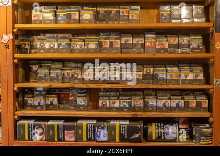 Middleharnis, Niederlande - Oktober 2 2021: Zigarettenschachteln und Tabakzubehör im Regal eines Tabakwarenladen Stockfoto