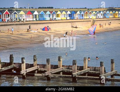 1999 Archiv close up Magier von großen Holz 1990er Wellenbrecher Groyne Struktur in der Nordsee Schutz der Küste & Küstenlinie in Southwold Badeort mit Menschen schwimmen und Windsurfen farbenfrohe Strandhütten dahinter auf der Betonwand Promenade In den 90er Jahren Blue Sky Summer Day Archivansicht der Suffolk Küste in East Anglia England Großbritannien Stockfoto