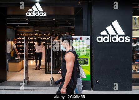 Hongkong, China. Oktober 2021. Fußgänger kommen an der deutschen multinationalen Sportartikelmarke Adidas-Store und -Logo in Hongkong vorbei. (Foto von Budrul Chukrut/SOPA Images/Sipa USA) Quelle: SIPA USA/Alamy Live News Stockfoto