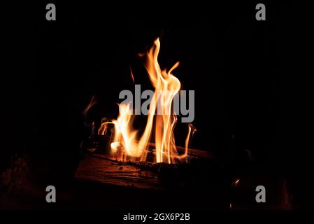 Feuer im Kamin auf dunklem Hintergrund. Brennholz in Flammen. Eine intime Atmosphäre am Kamin. Stockfoto