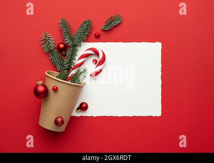 Weihnachtskarte mit Rahmen auf rotem Hintergrund und Weihnachtsschmuck. Flach liegend, Draufsicht und Platz zum Kopieren von Text Stockfoto