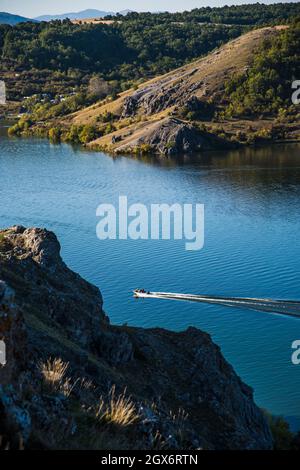 Ein Boot, das durch einen See raste. Ein See, Meer, Küste zwischen Bergen, Felsen, Natur in Bulgarien. Schöner sonniger Tag Stockfoto