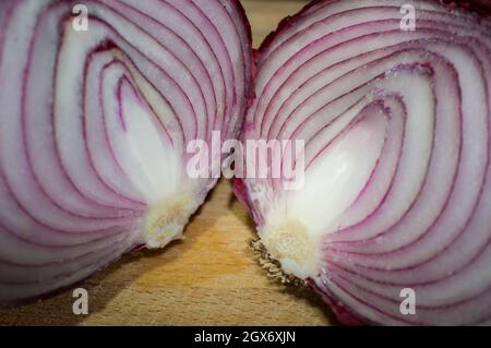 Schnittmengen von rohen roten Zwiebeln. Nahaufnahme über Holzschneidebrett Stockfoto