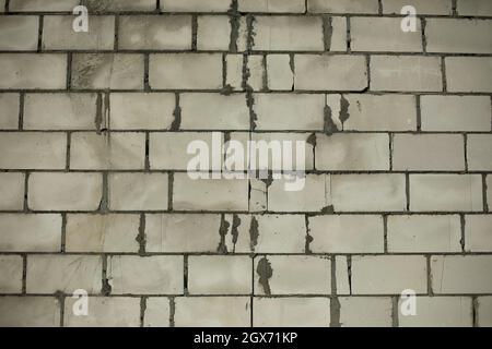 Wand aus Betonblöcken. Die Wand des Gebäudes auf der Baustelle. Nicht ausgekleidete Oberfläche des Hauses. Zementierte Nähte aus Mauerwerk. Stockfoto