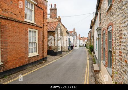 High Street in Blakeney Dorf ist eine charmante Straße mit historischen Häusern mit gerenderten Backstein oder Feuerstein Fassaden voller Charakter, Norfolk, England. Stockfoto