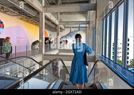 Frau auf der Rolltreppe unter einem Shark-Modell aus dem Film Jaws, das im Academy Museum of Motion Picturs in Los Angeles, Kalifornien, gezeigt wird Stockfoto