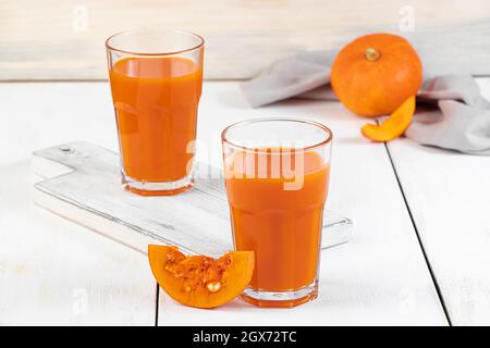 Zwei Gläser Kürbissaft auf weißem Holzhintergrund. Pflanzliches Detox-Getränk für eine gesunde Ernährung. Veganer Smoothie. Stockfoto