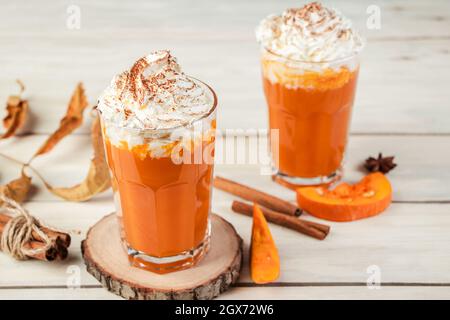 Kürbis Latte mit Schlagsahne auf hellem Holzhintergrund. Scharf würziger Smoothie. Veganes Getränk mit Gemüse. Stockfoto