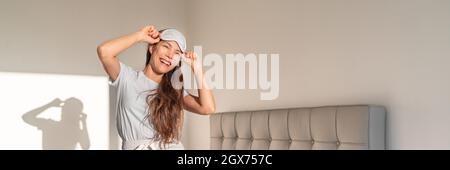 Glückliche Frau, die im Bett tanzt und das Banner mit der Schlafmaske trägt. Schlafzimmer junge Mädchen Lifestyle im Schlafanzug Stockfoto