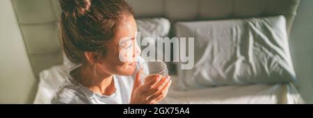 Fröhliche Frau zu Hause Lifestyle trinken Morgen Kaffee im Bett Wochenende entspannend Wake-up Banner Panorama. Asiatische Mädchen genießen Frühstück im Bett Stockfoto