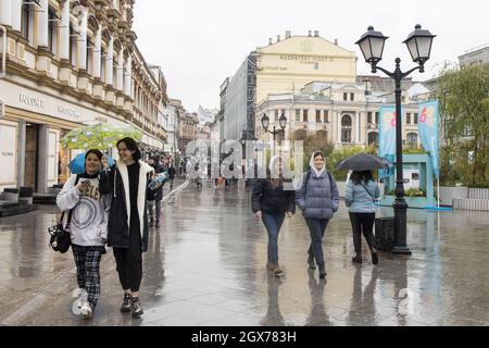 MOSKAU, RUSSLAND - 12. september 2021: Zwei Mädchen mit einem Regenschirm gehen die Straße Kuznetsky Most entlang, reden und lachen Stockfoto