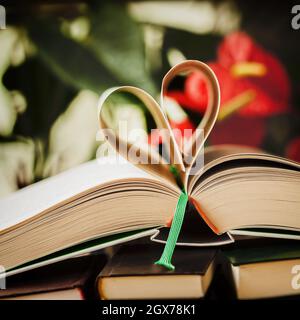 Offene Buch- und herzförmige Papierseiten, heller abstrakter Hintergrund Stockfoto