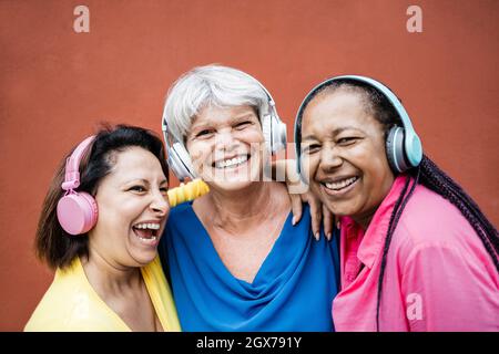 Multirassische ältere Frau, die Spaß hat, Playlists mit Kopfhörern zusammen zu hören - Senioren Lifestyle-Konzept - Fokus auf das Gesicht der Frau in der Mitte Stockfoto