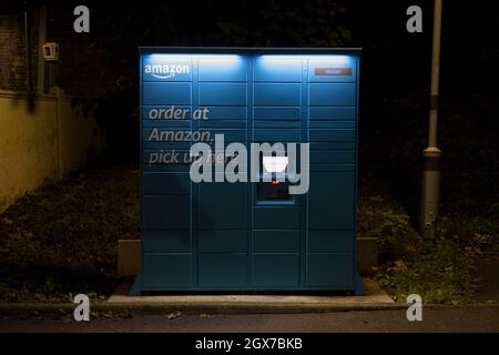 Amazon Hub locker gesehen in der Nacht auf dem Parkplatz des Kenley Bahnhof, South London. Stockfoto