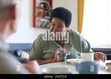 Porträt einer älteren afroamerikanischen Frau, die im Speisesaal des Pflegeheims das Frühstück genießt Stockfoto