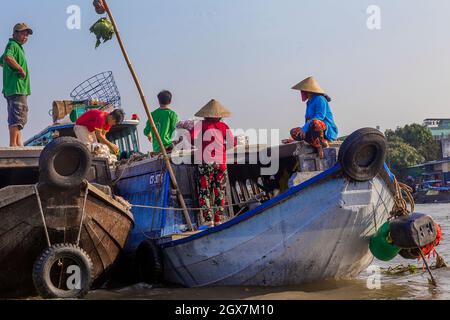 Sonnenaufgang trifft sich mit anderen Booten auf dem schwimmenden Cai Rang Markt, während sie die Früchte zeigen, die sie haben, indem sie sie hoch in die Luft auf einen Stock legen. Stockfoto