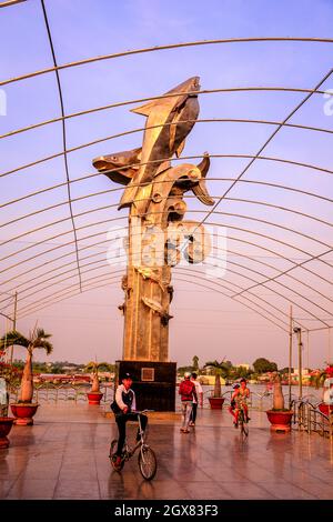 Kinder spielen um eine große Fischstatue auf den Docks von Chau Doc im Mekong. Stockfoto