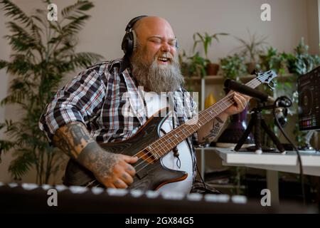 Fröhlicher Gitarrist mit Übergewicht spielt Musik Aufnahme neuer Song im Heimstudio Stockfoto