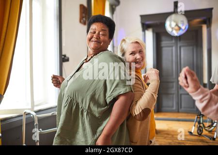 Eine Gruppe lächelnder älterer Frauen, die während ihrer Aktivitäten im Altersheim tanzen und Platz kopieren Stockfoto