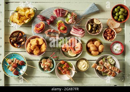 Draufsicht auf verschiedene Snacks mit Kebabs in der Nähe von Meeresfrüchten und gebratenes Hähnchen, serviert in Schüsseln auf dem Tisch mit verschiedenen Würstchen Stockfoto