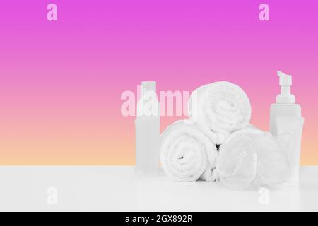 Stapel Handtücher, Flaschen mit Shampoo auf weißem Tisch Stockfoto