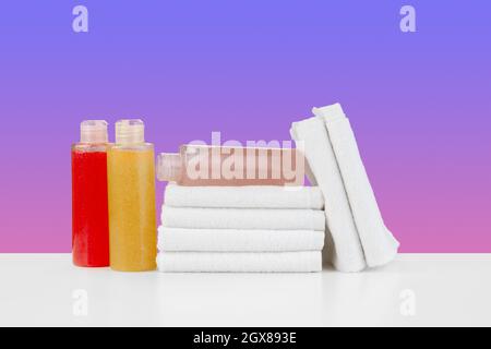 Stapel Handtücher, Flaschen mit Shampoo auf weißem Tisch Stockfoto
