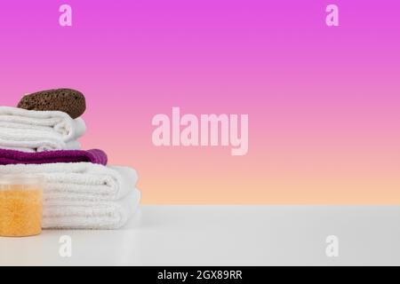 Stapel Handtücher, Flaschen mit Shampoo auf weißem Tisch Stockfoto
