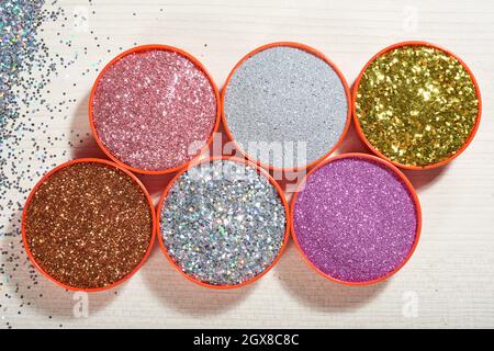 Direkt über Ansicht von bunten dekorativen glitzert in Containern auf Holztisch, Scrapbooking-Konzept Stockfoto