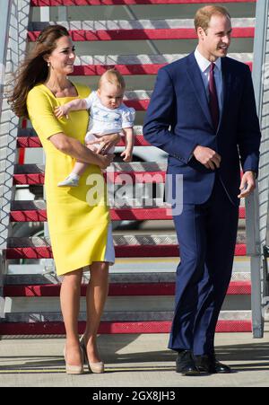 Catherine, Herzogin von Cambridge, mit dem Baby Prinz George, und Prinz William, Herzog von Cambridge, treffen am 16. April 2014 zu Beginn einer Australienreise am Flughafen von Sydney ein. Die Herzogin trägt ein leuchtend gelbes Roksanda Llincic Kleid. Stockfoto