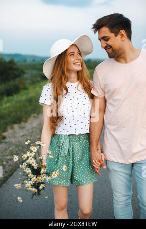 Schönes Nahaufnahme-Foto von einem Paar auf der Straße, das Blumen hält. Frühjahrskonzept. Frühlingsblumen. Liebeskonzept. Frohe, liebevolle Familie. Sommerkonzept. Straße Stockfoto