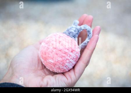 Frau hält in der Hand stieg Neujahr Ball amigurumi. Aus Plüschgarn gestricktes Plüschtier für die Weihnachtsdekoration. Handgefertigte Weihnachtsgeschenke. Erstellen eines Stockfoto