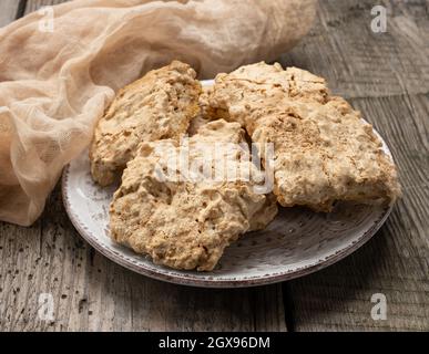 Quadratisch gebackene Plätzchen liegen auf einem runden Teller auf dem Tisch, polieren Plätzchen, aus nächster Nähe Stockfoto