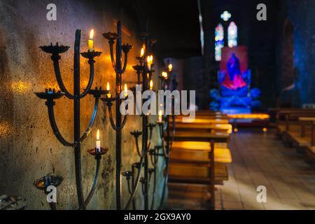 Selektiver Fokus auf Votivkerze auf Kerzenleuchtern mit hellem Glanz, verschwommenem Hintergrund des Innenraums der St Marys Cathedral in Killarney, Kerry, Irland Stockfoto