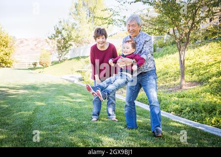 Glücklich chinesischen Großeltern Spaß mit ihren Enkel Mischlinge außerhalb. Stockfoto