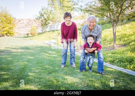 Glücklich chinesischen Großeltern Spaß mit ihren Enkel Mischlinge außerhalb. Stockfoto