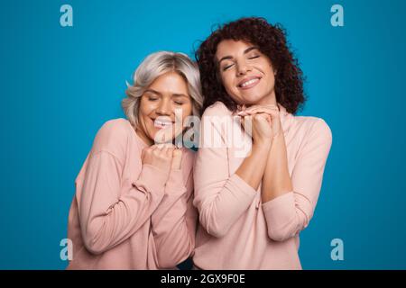 Schönes Porträt einer lockigen Schwester auf der Studiowand, die zusammen träumt. Wunderschönes Porträt. Familienkonzept. Stockfoto
