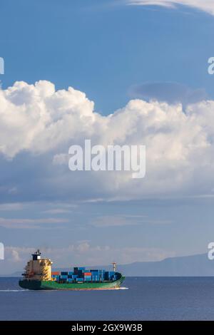 Frachtschiff in der Nähe Capo Peloro Leuchtturm in Punta del Faro an der Straße von Messina, nordöstlichste Landzunge von Sizilien, Italien Stockfoto