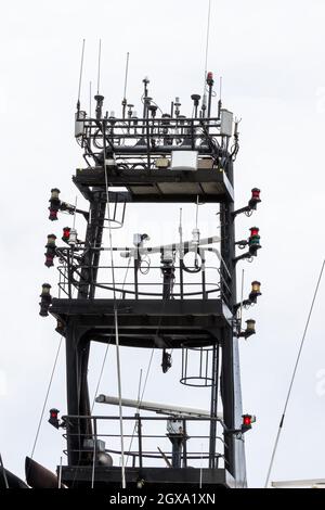 Hauptmast des Schiffes von unten betrachtet. Beleuchtung für eingeschränkte Manövrierfähigkeit leuchtet. Mehrere Arten von Antennen und Kabeln. Stockfoto