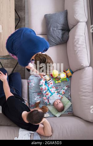 Familie, Technologie und Personen Konzept - Blick von oben auf die glückliche Mutter und Vater nehmen Bild von baby boy mit Smartphone auf dem Sofa zu Hause Stockfoto