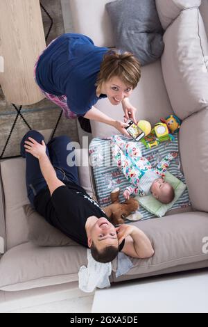 Familie, Technologie und Personen Konzept - Blick von oben auf die glückliche Mutter und Vater nehmen Bild von baby boy mit Smartphone auf dem Sofa zu Hause Stockfoto