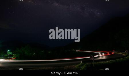 Vegicle leichte Wanderwege in der Nacht auf der belebten Landstraße Kurve lange Belichtung Stockfoto