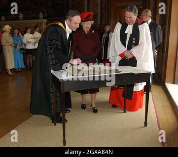 Die britische Königin Elizabeth II. Wird in der Great Hall im Hampton Court Palace mit einer King James-Bibel aus dem Jahr 1651 dargestellt. Der Palast feiert den 400. Jahrestag der Hampton Court Konferenz Stockfoto