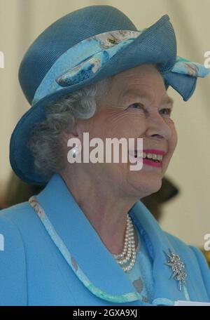 Die britische Königin Elizabeth II. Lächelt, als sie eine innovative Theateraufführung sieht, die mit Drama das Vertrauen der Kinder in die Piece Hall in Halifax, Yorkshire, am Donnerstag, den 27. Mai 2004, stärkt. Zuvor besuchte sie die Halifax High School, wo ein 11-jähriger Schüler ihr eine schicke Schülerin überreichte - nachdem er sich eine Münze angeschaut hatte, um zu sehen, wer sie war. Stockfoto