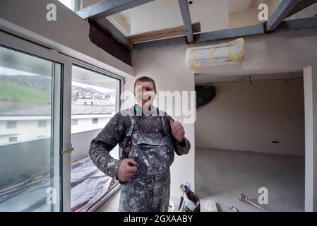 Portrait von Fachangestellten mit schmutziger Uniform in der Wohnung, die im Bau ist, Umbau, Renovierung, Erweiterung, Wiederherstellung, Überholung und Stockfoto